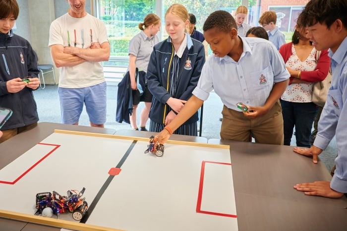 Picture of a group of students interacting with electronics hardware and laptops.